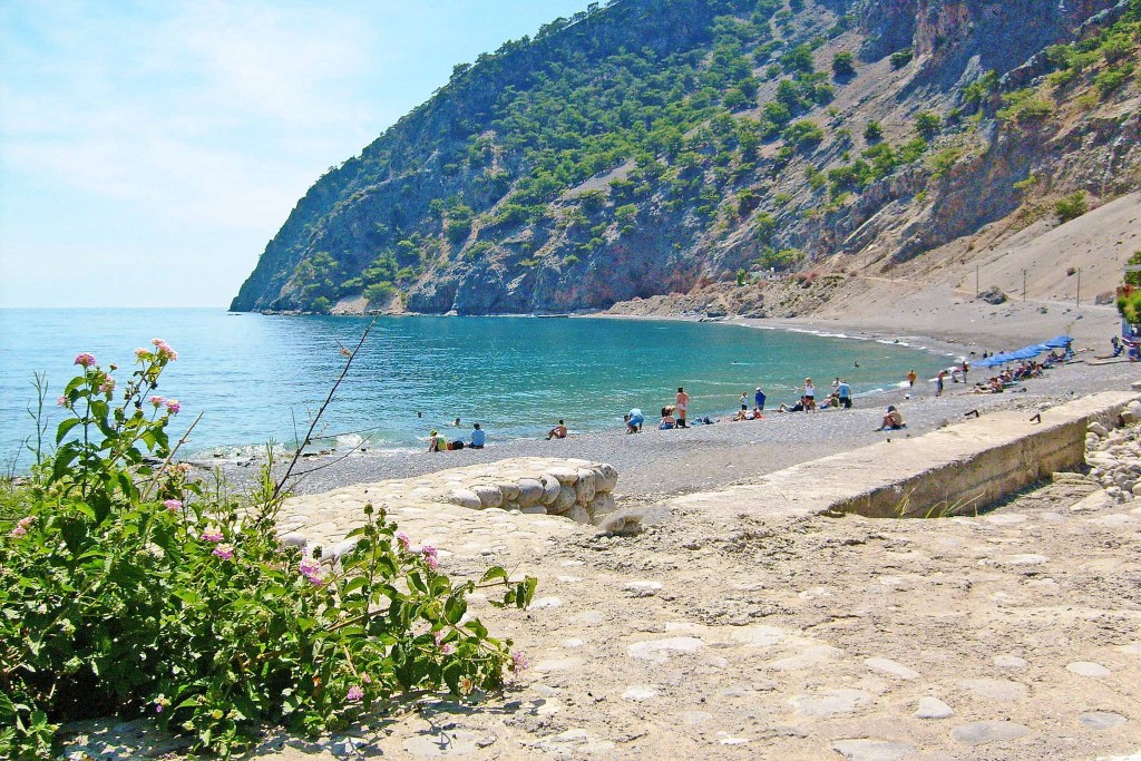People relaxing on the shore of a beach with blue-green ocean water