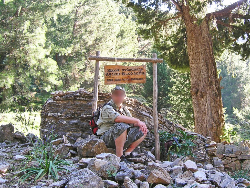Hiker in front of a wooden sign with green forest trees in the backgroun 