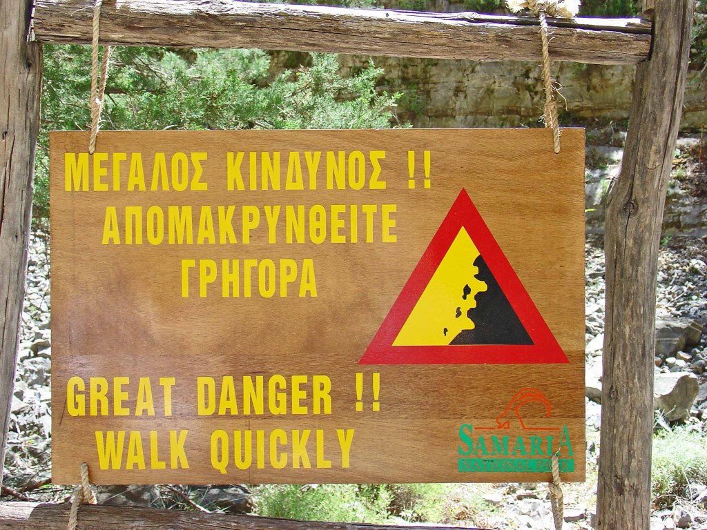 Danger sign warning of falling rocks and telling hikers to walk quickly