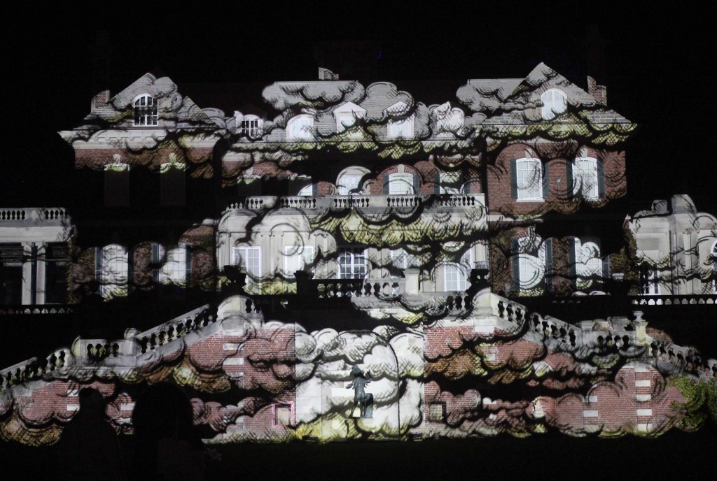 Mansion at night illuminated with white clouds.