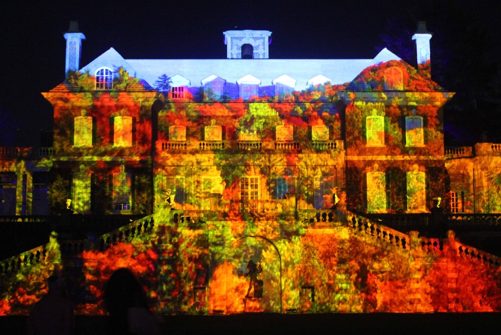 Mansion at night illuminated with red, green, yellow, and orange colors.