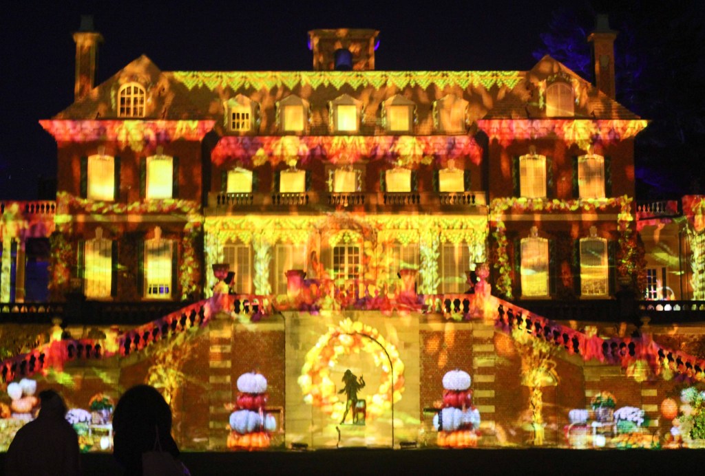 Mansion at night illuminated with red and yellow lights.