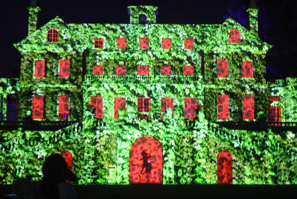 Mansion at night illuminated with green and red lights.
