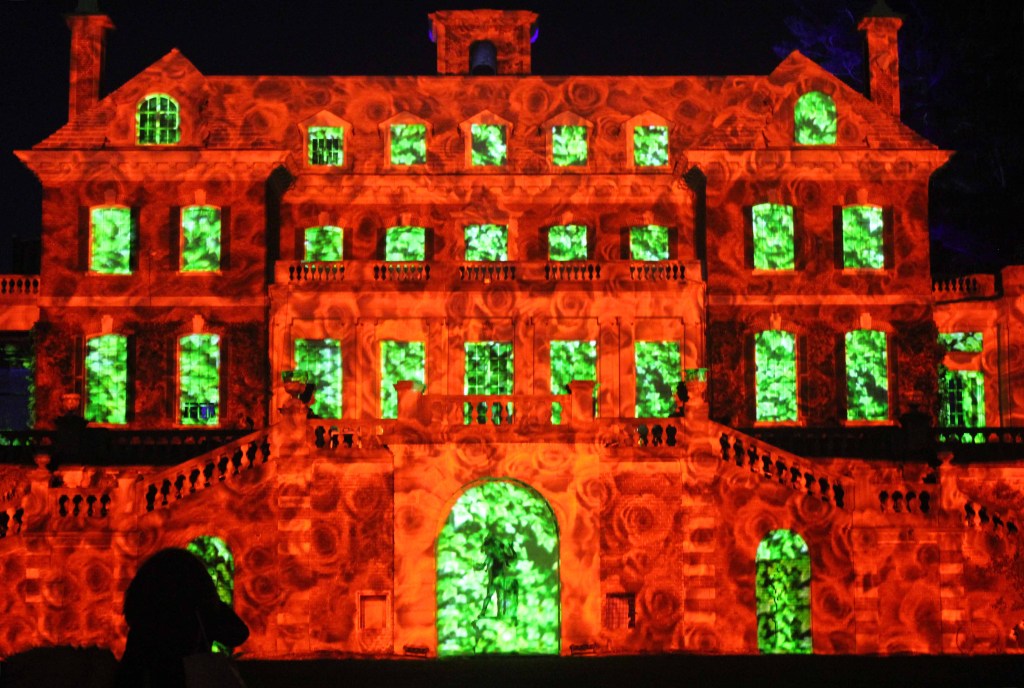 Mansion at night illuminated with red and green lights.