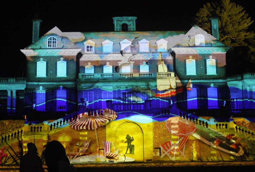 Mansion at night illuminated with a summer beach scene.