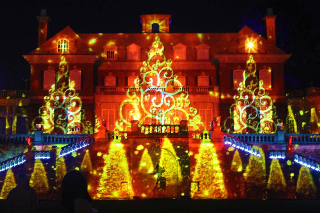 Mansion at night illuminated with Christmas trees in yellow lights.